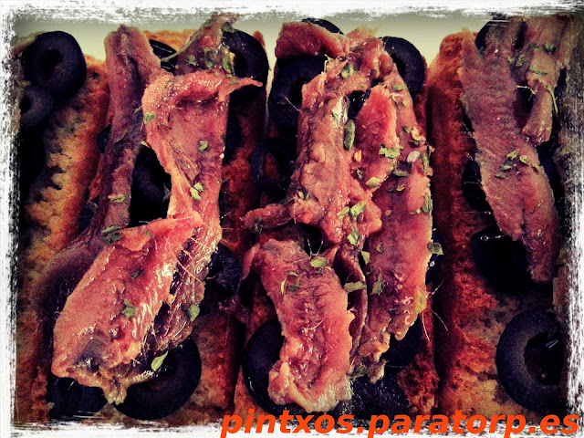 Tosta de anchoas sobre aceitunas negras